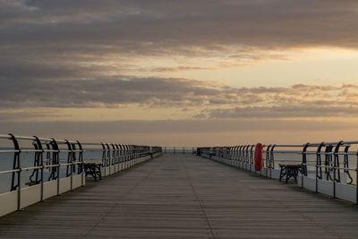 Pier over sea against sky during sunset