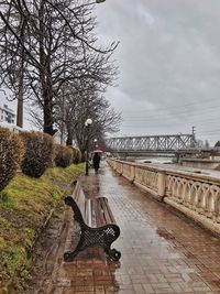 View of park bench by bridge against sky