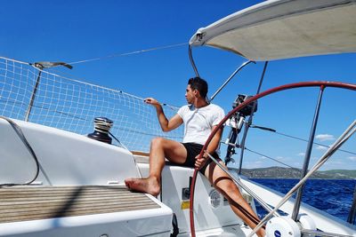 Low angle view of man sitting in sailboat on sea against sky