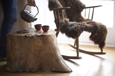 Woman's hand pouring tea into tea bowls in an individual living room