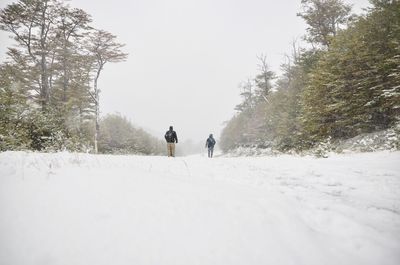 Rear view of people walking on snow 
