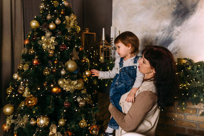 Portrait of young woman standing by christmas tree