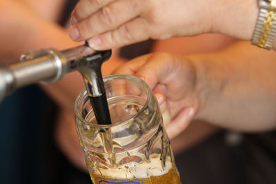 Cropped hands filling glass with beer from tap