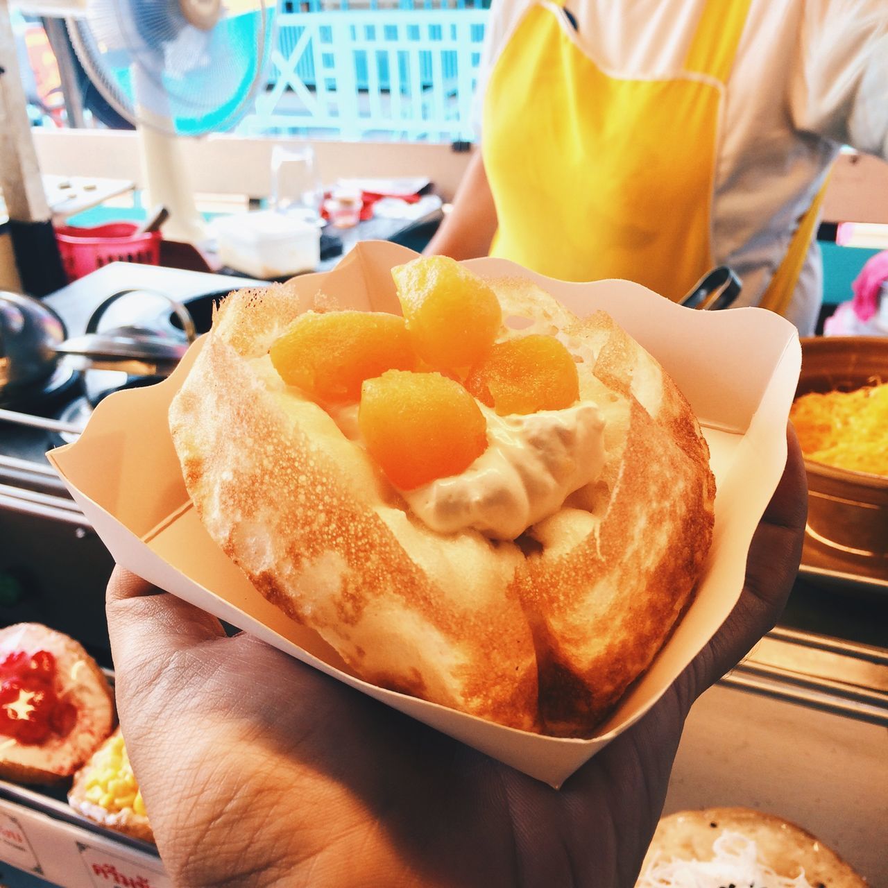 CLOSE-UP OF PERSON HOLDING ICE CREAM ON TABLE