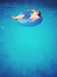 Shirtless boy relaxing in inflatable ring at swimming pool