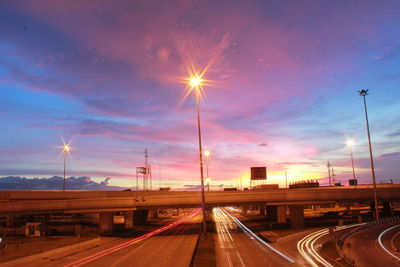 Light trails on road against sky at sunset