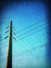 Low angle view of electricity pylon against blue sky