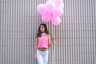 Portrait of young woman with pink balloons