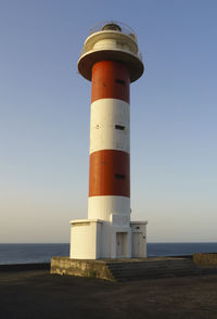 Lighthouse by sea against sky