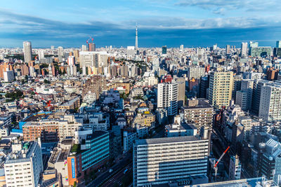 High angle view of city buildings against cloudy sky