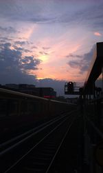 Railroad tracks against cloudy sky