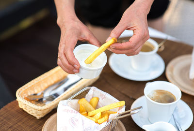 Midsection of woman having french fries at table