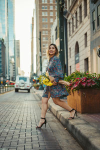 Full length portrait of woman on building in city