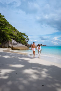 Woman walking on beach against sky