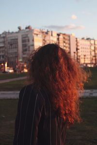Rear view of woman standing by river against sky