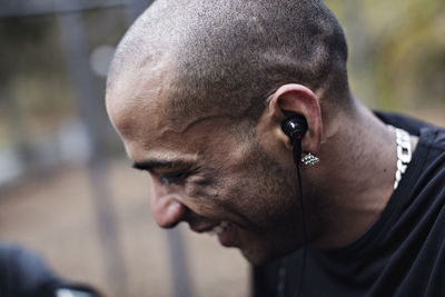 Side view of happy male athlete wearing in-ear headphones at forest