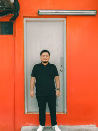 Portrait of young man standing against wall