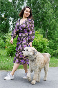 Smiling woman walking with dog on road