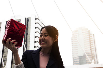 Low angle view of woman holding gift box outdoors
