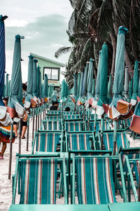 Row of chairs on beach against sky