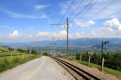 Railroad tracks by mountain against sky