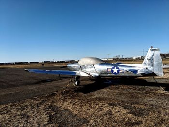 View of airplane on airport runway against clear blue sky