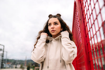 Portrait of young woman standing against sky