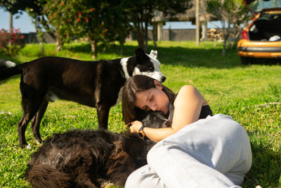 Woman kissing dog lying on grass
