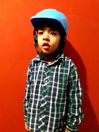Portrait of cute boy wearing hardhat against wall