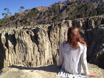 Rear view of woman sitting on rock