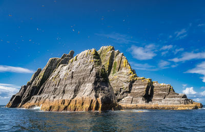 Rock formations by sea against blue sky