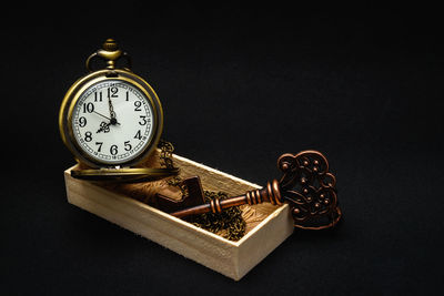 Close-up of clock on table against black background