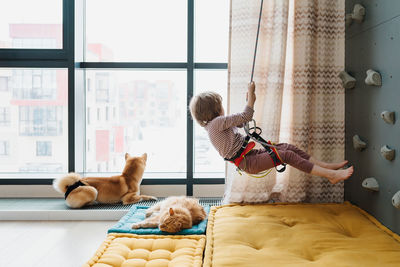 Young boy indoor rock climbing with his father instructor. hobby or home sport concept.