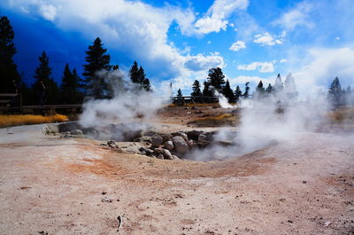 Steam emitting from hot springs against sky