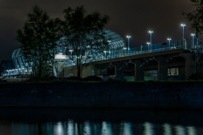 Illuminated bridge over river at night