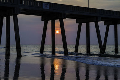 Silhouette pier over sea against sky at sunset