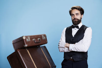 Portrait of young man standing against blue background