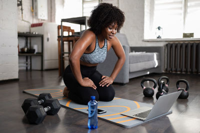 Sweaty black sportswoman watching video on laptop