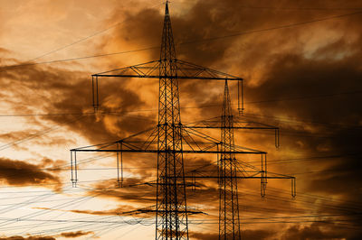 High voltage pylons for electricity and power against sky with dramatic clouds