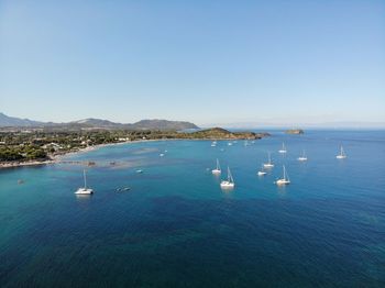 Sailboats in sea against clear blue sky