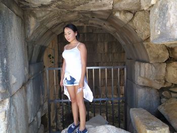 Young woman standing on rock by entrance