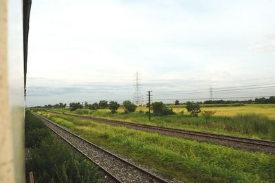 Railroad tracks on field against sky