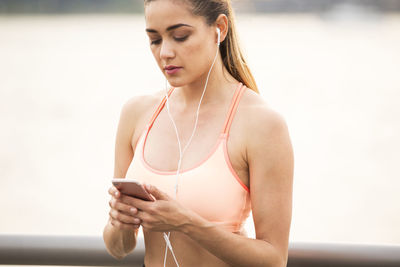 Woman using smart phone while exercising on bridge