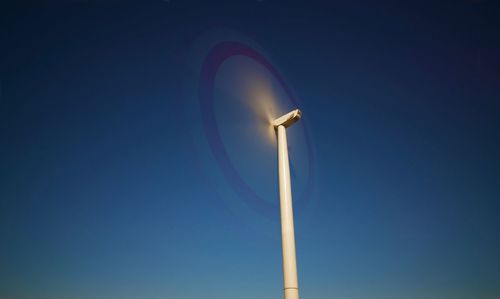 Low angle view of wind turbine against blue sky