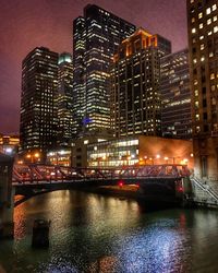 Illuminated buildings by river at night