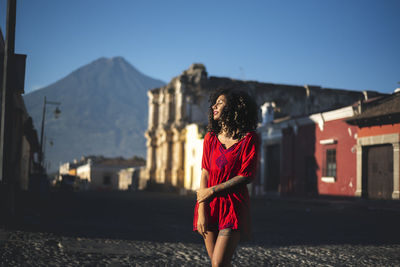 Woman standing against houses and mountains