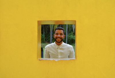 Portrait of smiling man standing against yellow wall
