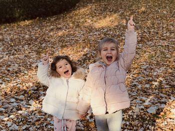 Smiling little girls sisters with gold leaves in fall 