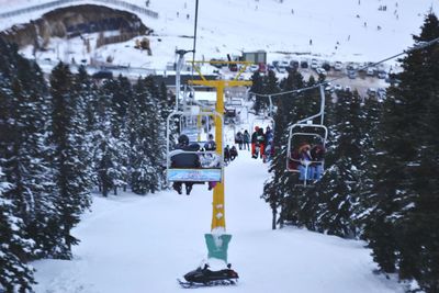 People in ski lift against sky during winter