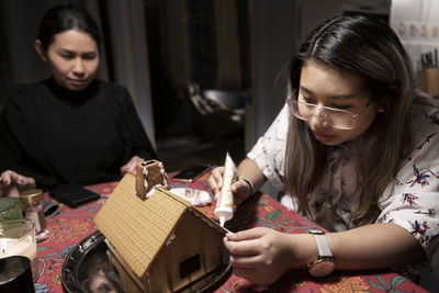 Women decorating gingerbread house